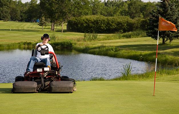golf course green and man on lawn mower